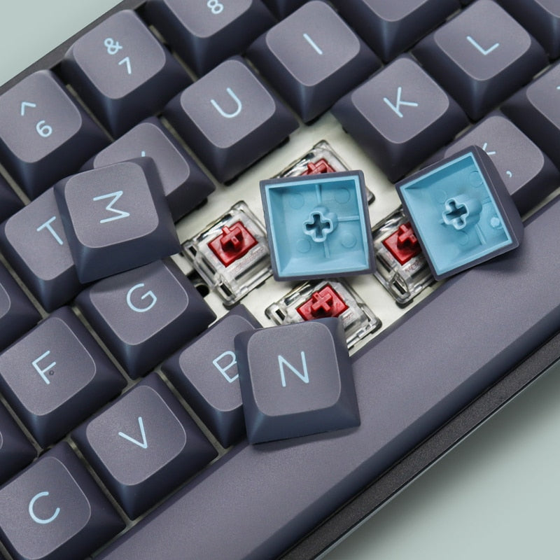 close up of a gaming mechanical keyboard showcasing dark blue pbt double-shot keycaps with brown mx switches underneath