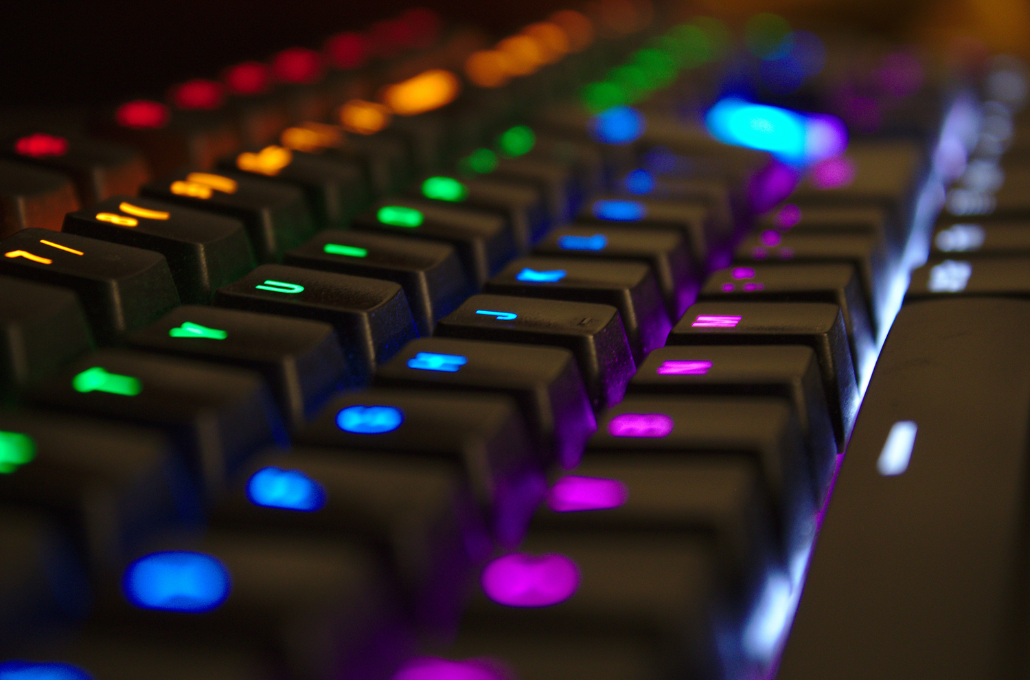 A close-up image of an RGB mechanical keyboard, focusing on the illuminated keycaps and switches, showcasing the vibrant, customizable lighting effects that enhance the typing and gaming experience.