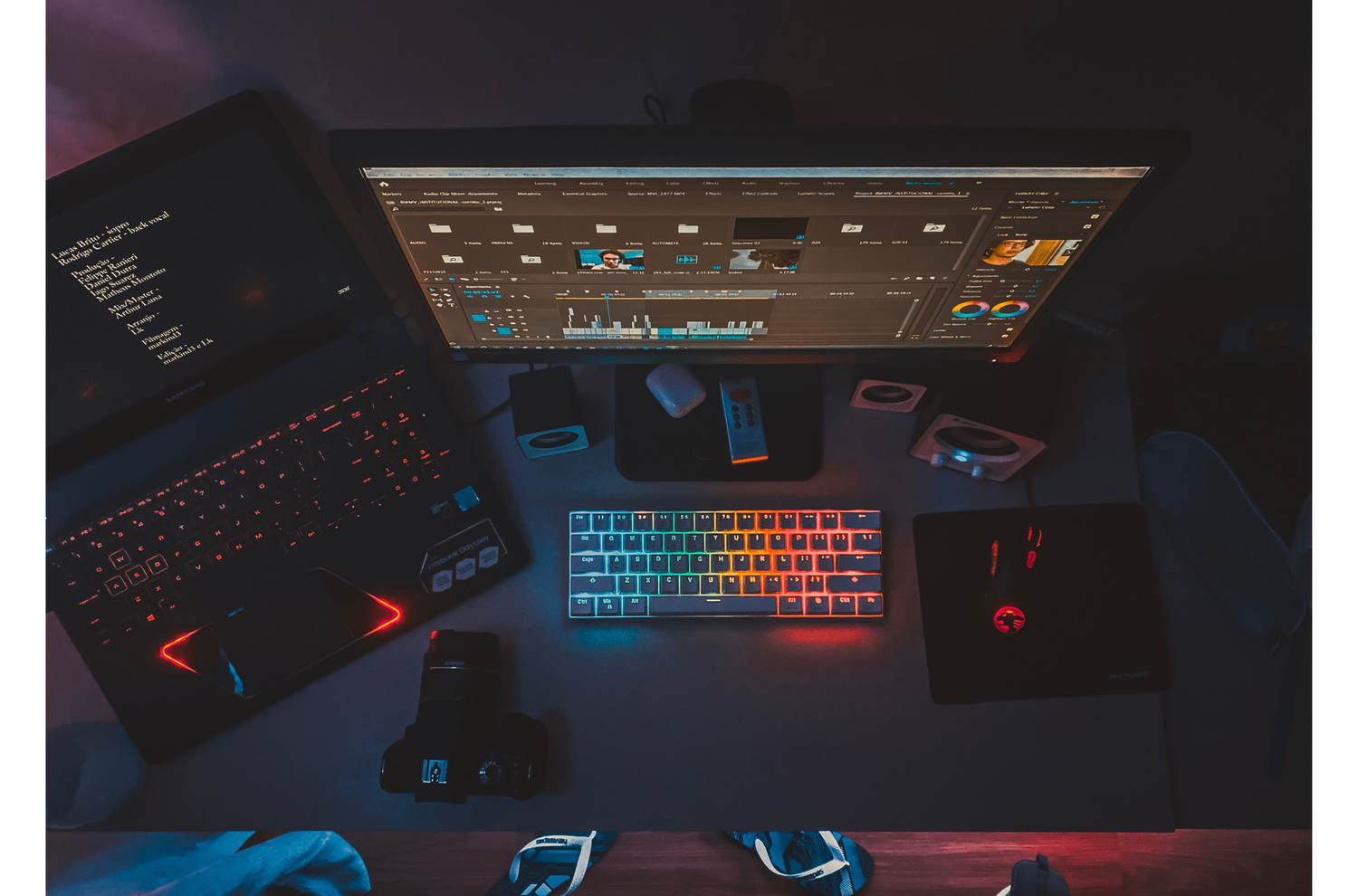 An overview image of a gaming and streaming setup, featuring a laptop with RGB lighting, a connected DSLR camera for high-quality streaming, and various peripherals like a keyboard, mouse, and headphones, all set up on a spacious desk