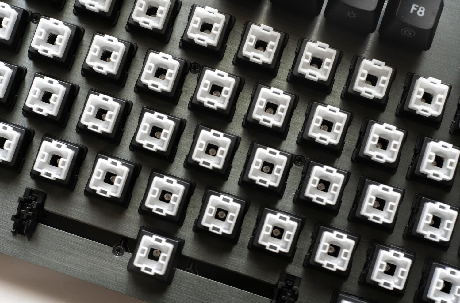 An image of a barebones mechanical keyboard with exposed key switches and no keycaps, revealing the underlying structure and switch mechanisms