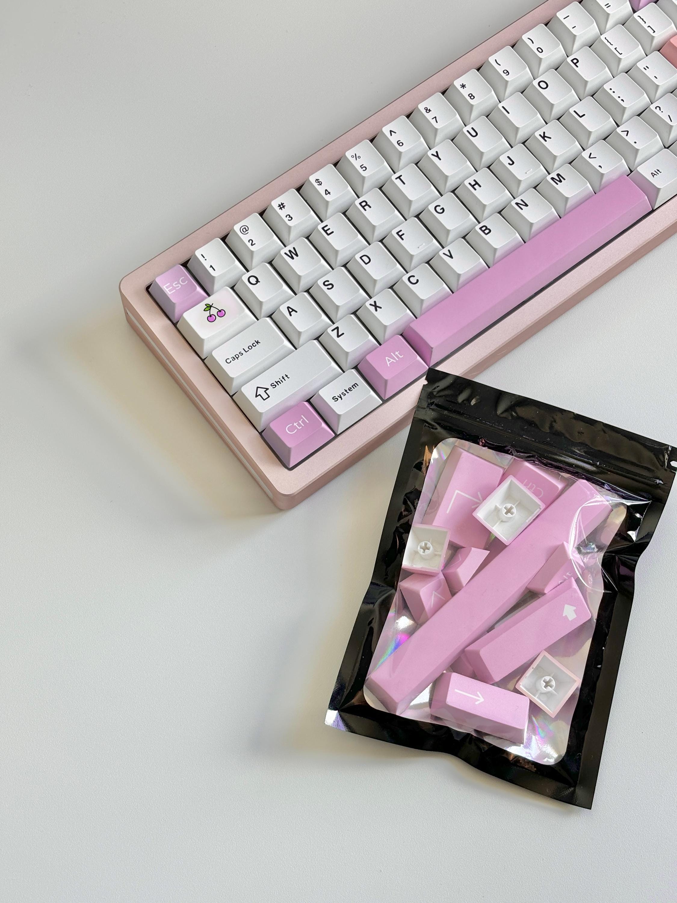 cute pink custom keycaps in zip-tie bag ready to ship next to white custom mechanical keyboard with pink keycaps